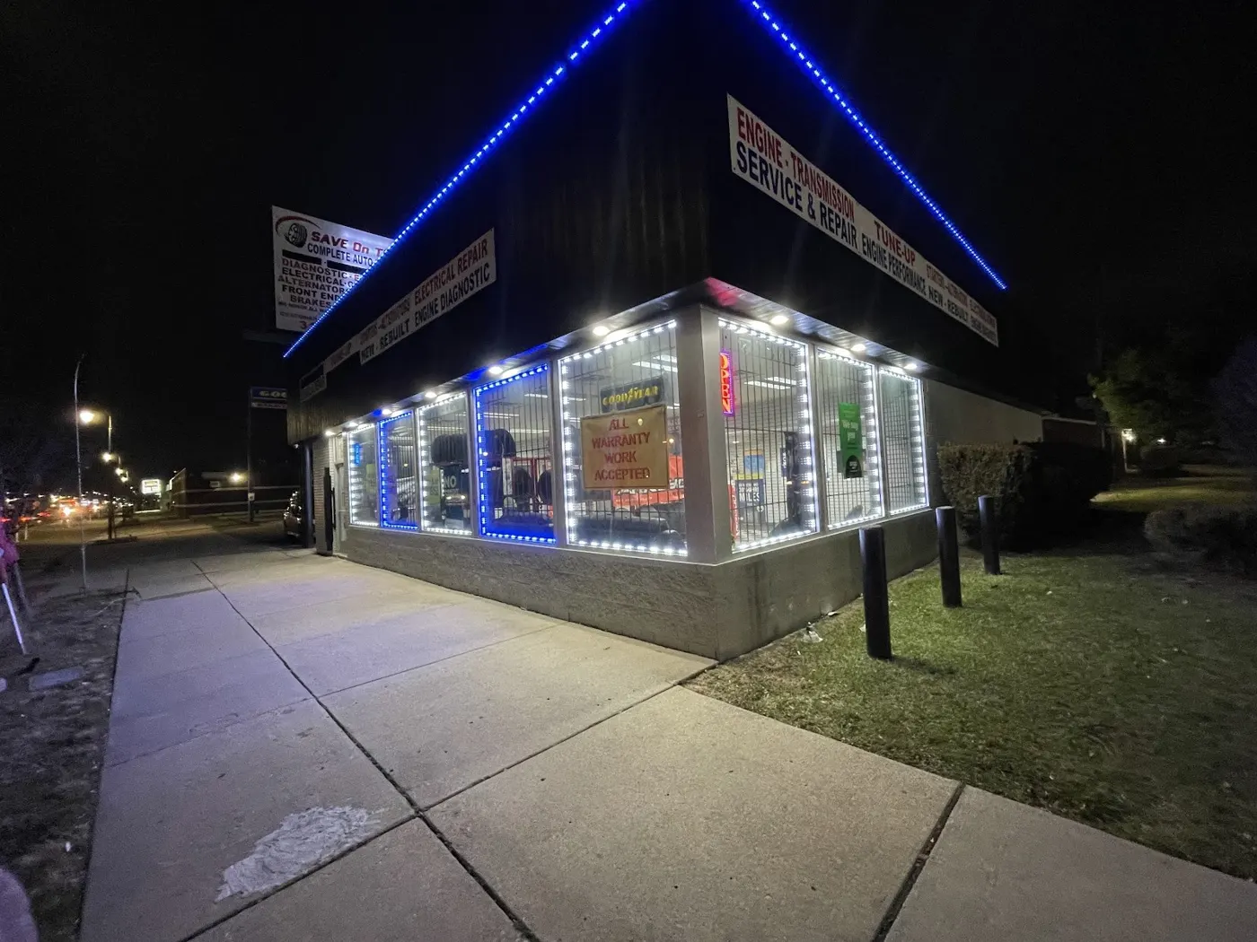 Save On Tire storefront at night on Grand River Avenue, lit up in blue with tires stacked out front